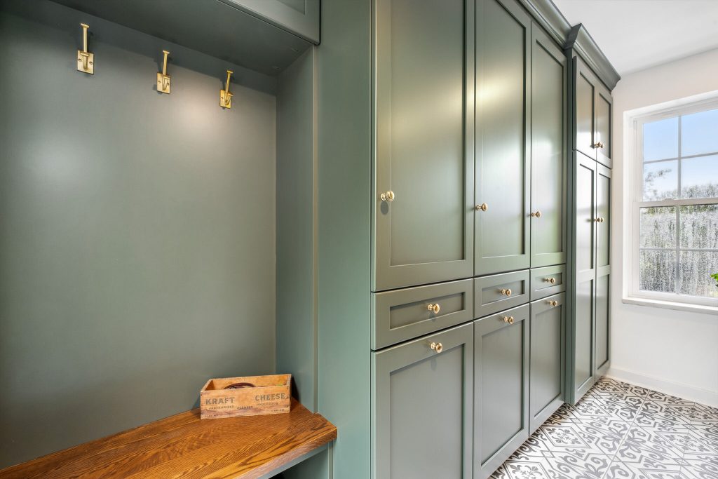 This home addition in Mt. Lebanon, PA included a functional mudroom and laundry room with green cabinetry, hooks and beautiful patterned tile.